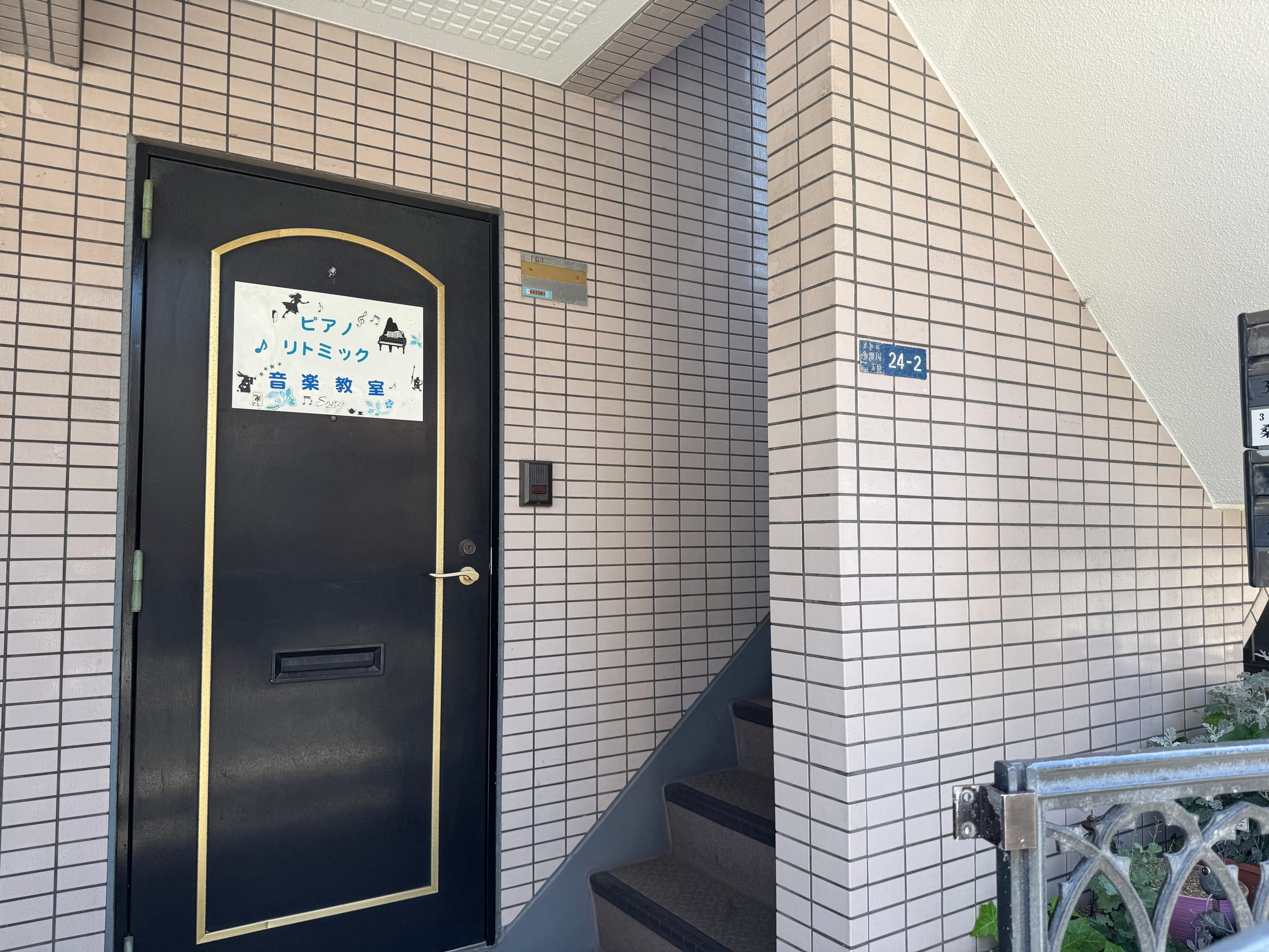 住所表示とピアノ教室の案内がある黒い玄関ドア